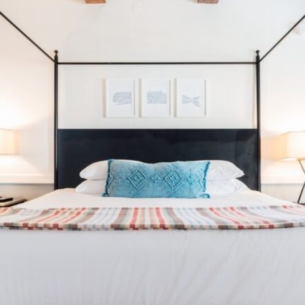 Bright bedroom with four poster bed, colorful pillows and lamps