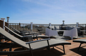 Rooftop deck with lounge chairs and outdoor seating under blue sky