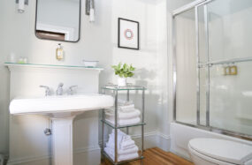 Clean bathroom with pedestal sink, glass shower and towel rack at Mercury Hotel