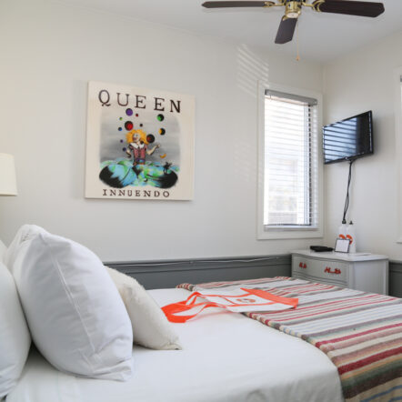 Bright guest room with striped bedding, wall art and TV at Mercury Hotel