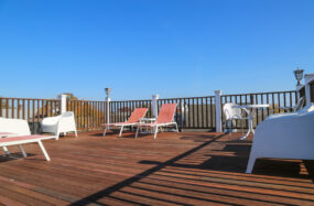 Sunny rooftop deck with white lounge chairs