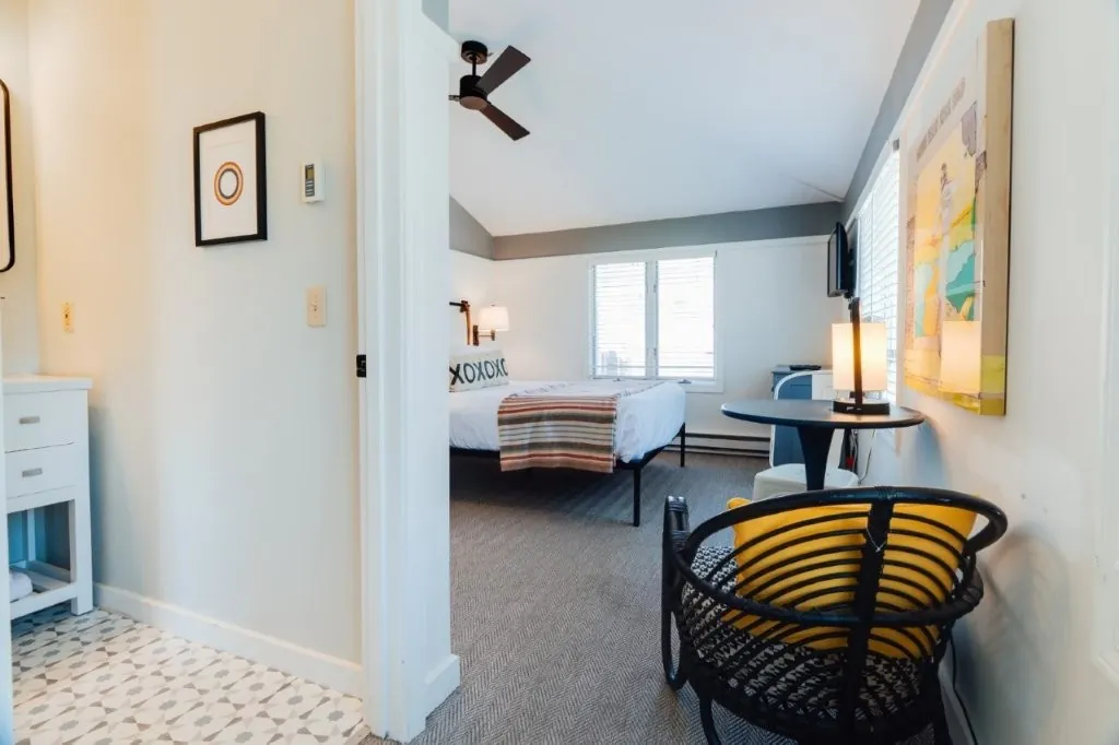 Standard queen room with sloped ceiling, yellow accents and ceiling fan
