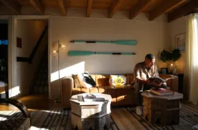 Guest reading in warmly lit lobby with wall mounted oars at Mercury