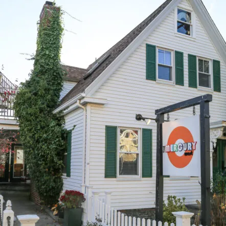 Exterior of Mercury with white siding, green shutters and front sign