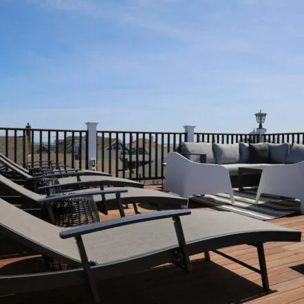 Rooftop deck with lounge chairs and outdoor seating under blue sky