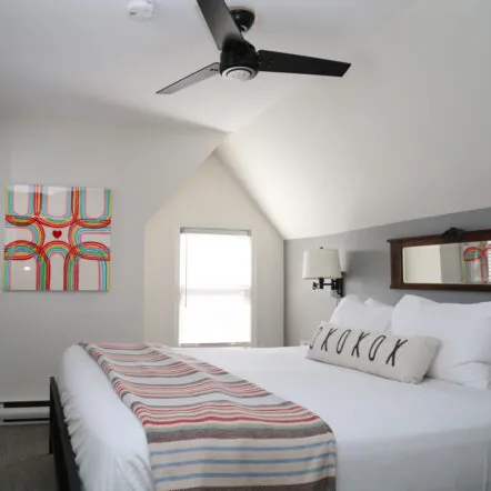 Bright bedroom with king bed, ceiling fan and modern art at Mercury Hotel