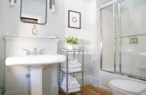 Clean bathroom with pedestal sink, glass shower and towel rack at Mercury Hotel