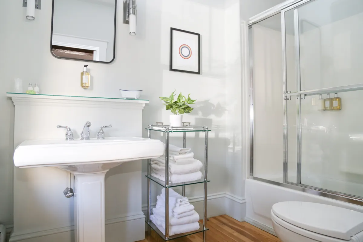 Clean bathroom with pedestal sink, glass shower and towel rack at Mercury Hotel