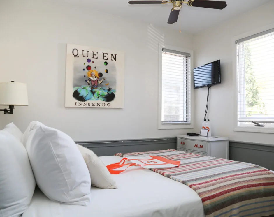 Bright guest room with striped bedding, wall art and TV at Mercury Hotel